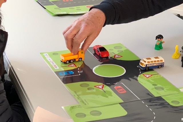 A hand driving toy car on road map.