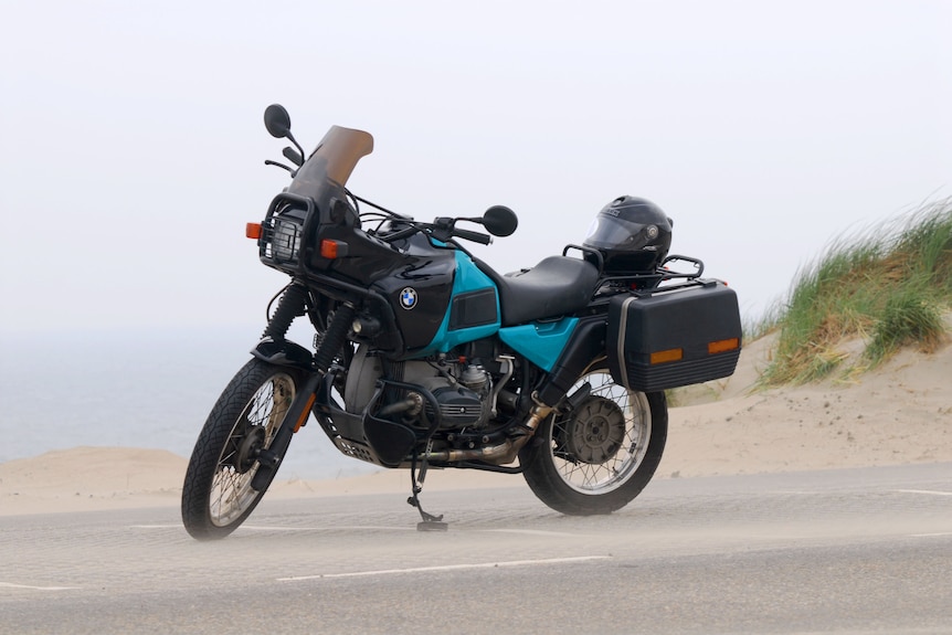 A large motorbike on its stand near a foggy beach