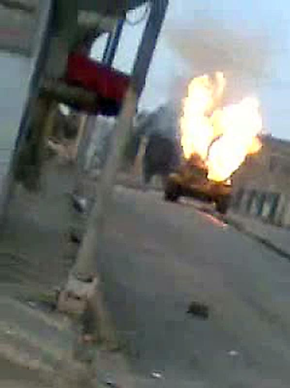 A Syrian army tank burns in a street of the city of Rastan.