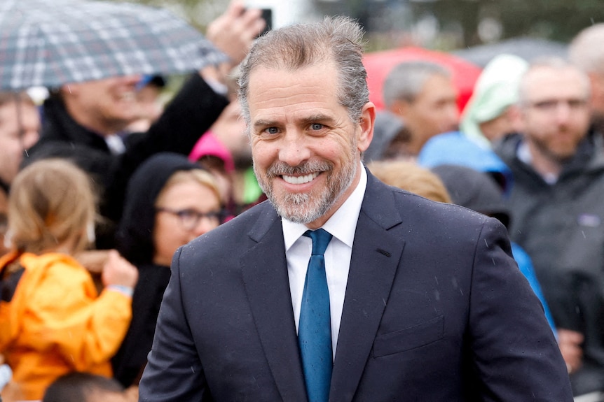 Hunter Biden is smiling at the camera in front a crowd. 