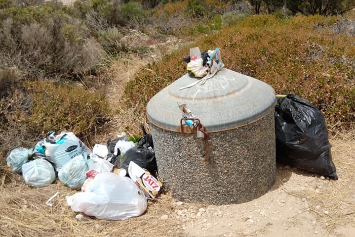 Rubbish fills a bin and sits beside it on the sand dunes at Coles Point