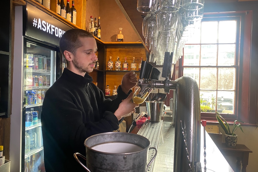 A bartender pours a beer.
