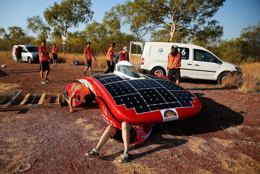 Team members from Luminos of the Stanford Solar Car Project dismantle their car.