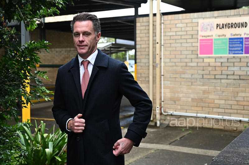 a man wearing an overcoat standing in the playground of a school looking at the camera