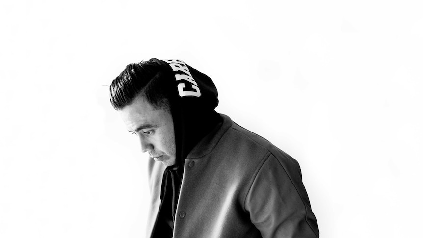 black and white photo of taku looking sideways in a baggy hoodie jumper