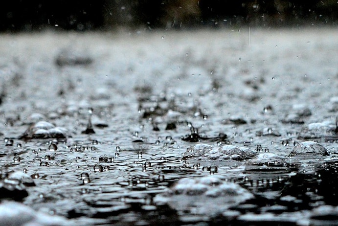 Close-up photo of raindrops hitting the surface of water.