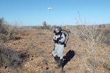 A man in a space suit tests a drone.