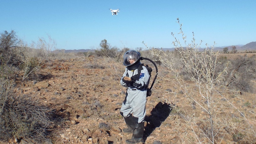 A man in a space suit tests a drone.