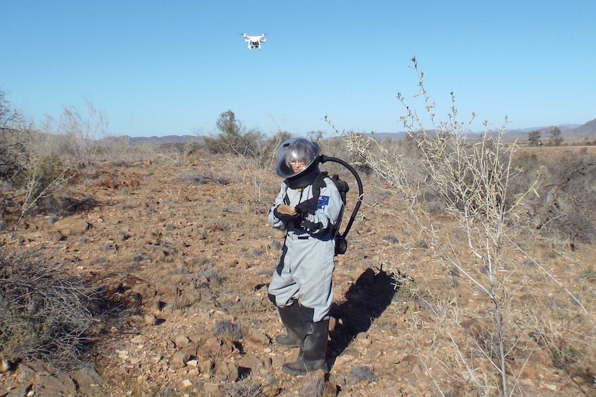 A man in a space suit tests a drone.