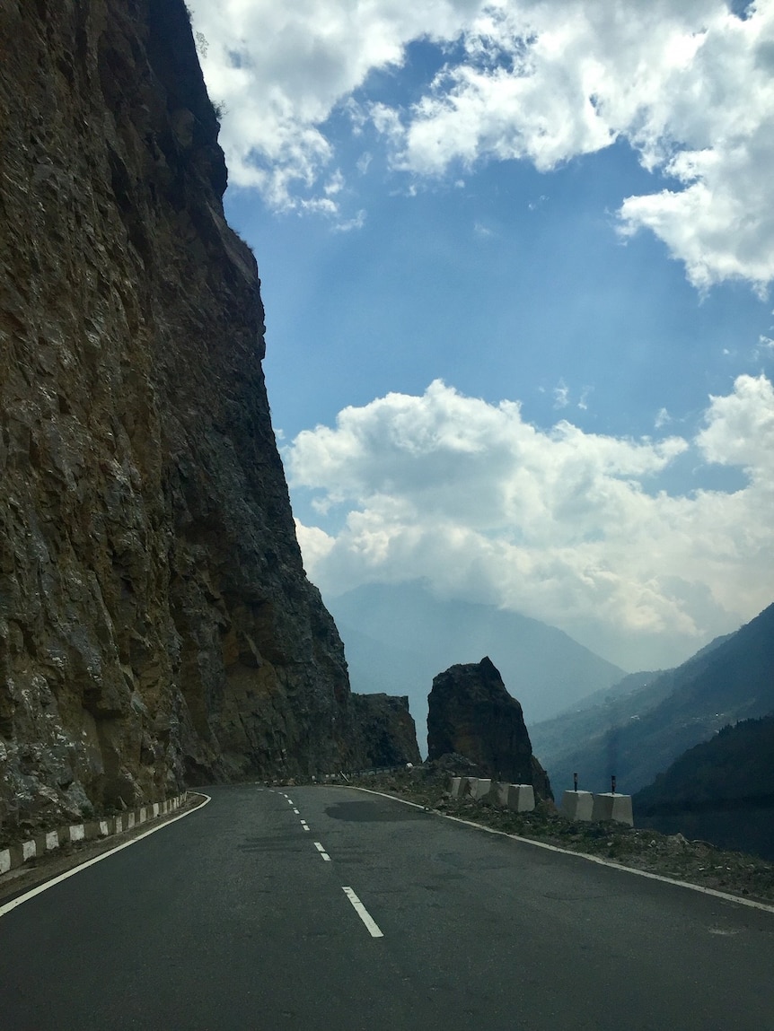 Photo of road with high steep cliff above.