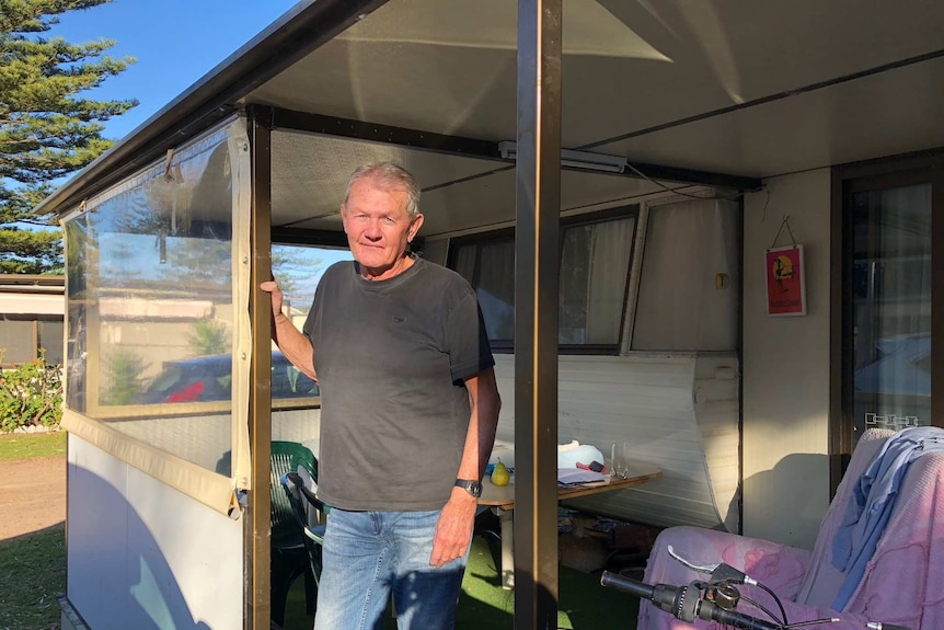 Caravan owner Dennis McKeown stands on the deck outside of his caravan at the Werri Beach Holiday Park in Gerringong.