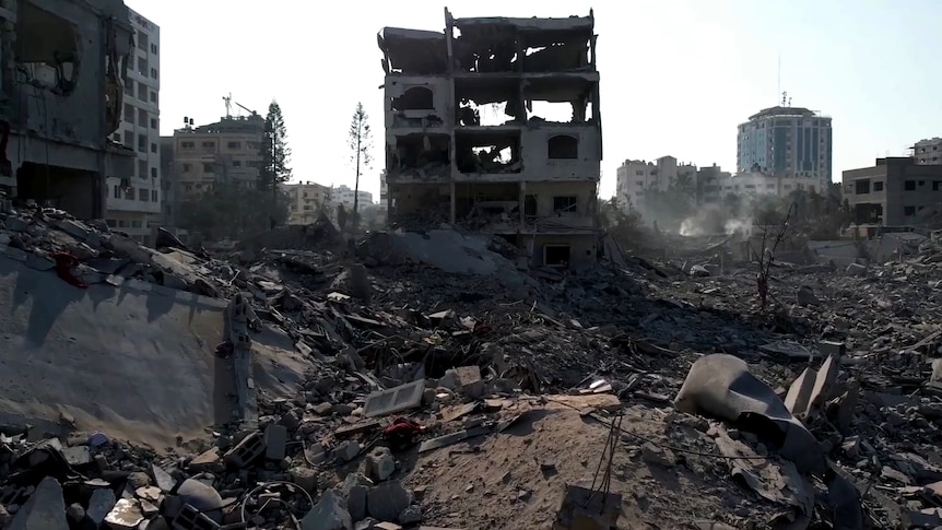 A destroyed apartment building sits among rubble in a city 