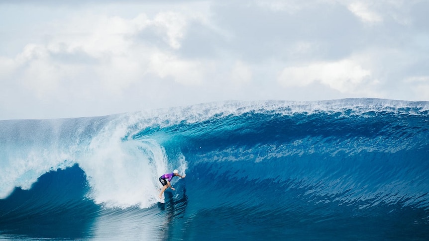 Australian surfer Owen Wright wearing a helmet as he drops into a large wave on his way to victory in Tahiti.