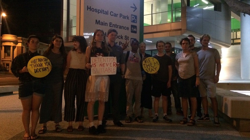 A group of people gathered outside the Lady Cilento Children's Hospital with signs.