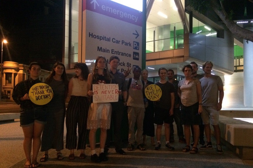 A group of people gathered outside the Lady Cilento Children's Hospital with signs.