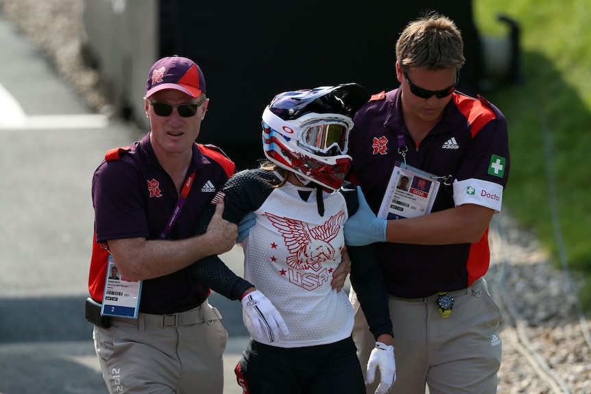 Alise Post is helped by a man on each side holding her arms