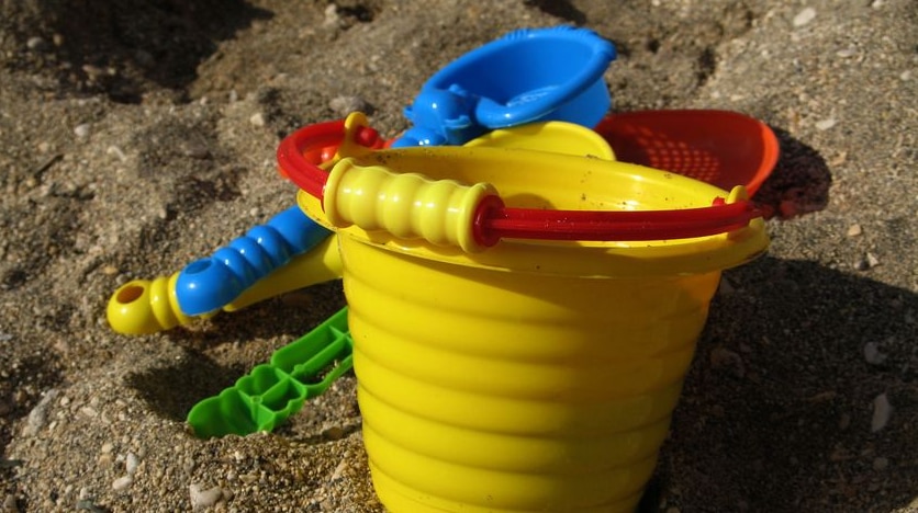 Generic photo of a child's toy bucket and spade sitting in the sand.