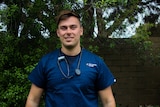 Jackson Heilberg, a young nurse standing outside smiling. He wears hospital scrubs with a stethoscope around his neck.