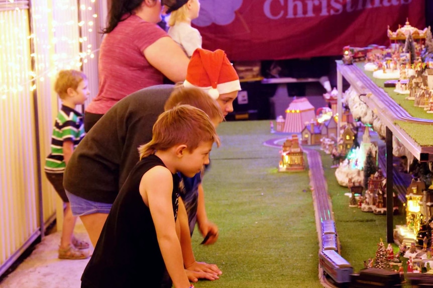Children looking at a toy train set up at a Christmas house.
