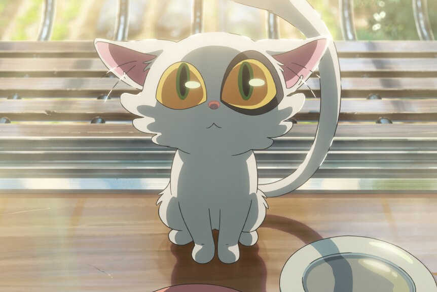 A still from an anime movie, where a white cat with large yellow-green eyes looks upwards, sitting near a plate.