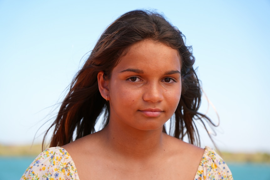 A young girl with brown hair looking at the camera