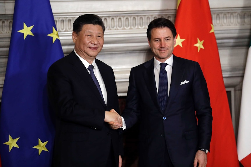 Chine4se President Xi Jinping and Italian PM Giuseppe Conte shake hands at the end of the signing ceremony in front of flags.