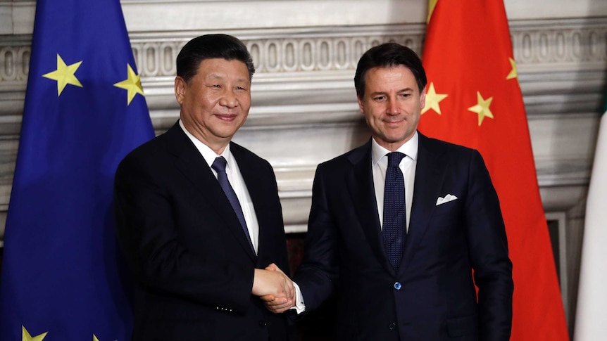 Chine4se President Xi Jinping and Italian PM Giuseppe Conte shake hands at the end of the signing ceremony in front of flags.