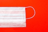 A disposable face mask on a plain background