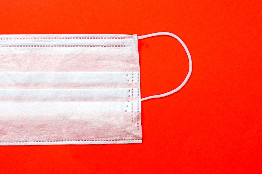 A disposable face mask on a plain background