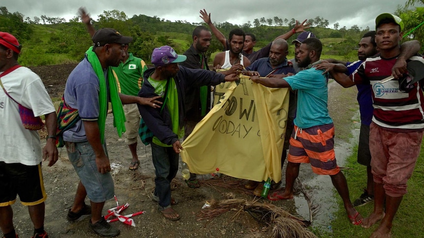 Protesters take down a banner that said the Kokoda Track was closed.