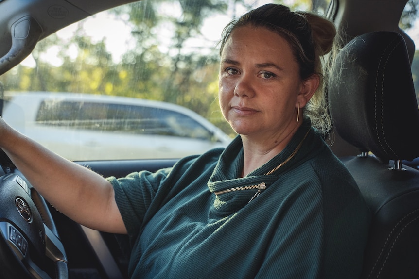 A woman looks unhappy as she sits in her car