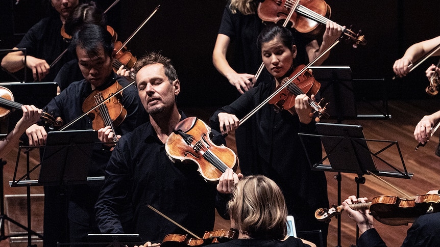 Violinist Richard Tognetti performs with the Australian Chamber Orchestra. His eyes are closed in contemplation.