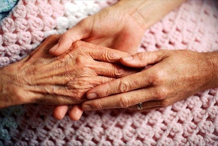 A woman's hand holding an elderly patient's hand.