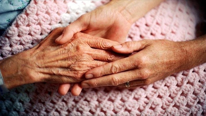 A woman's hand holding an elderly patient hand.