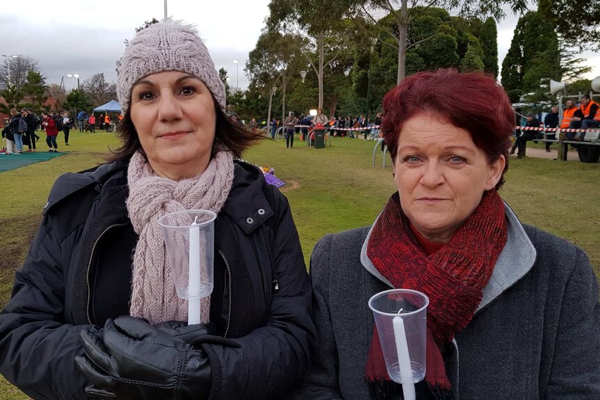 Two women stand with candles ready to be lit at Princes Park oval for the vigil for Eurydice Dixon.