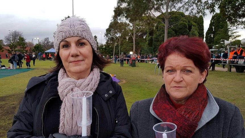 Two women stand with candles ready to be lit at Princes Park oval for the vigil for Eurydice Dixon.