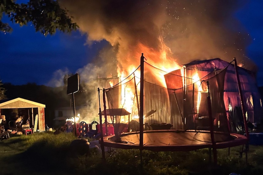 a shed on fire behind a trampoline.