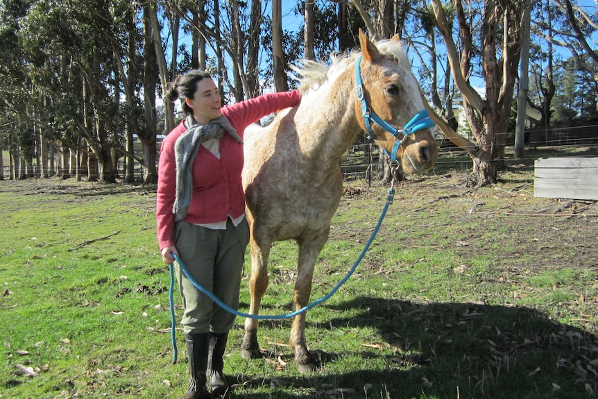A young woman standing next to a horse
