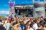 People dance in front of a stage at a music festival.