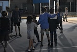 Young kids play on a basketball court