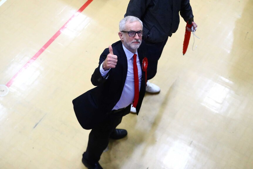 Jeremy Corbyn giving a thumbs up in a school gymnasium
