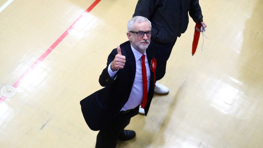 Jeremy Corbyn giving a thumbs up in a school gymnasium