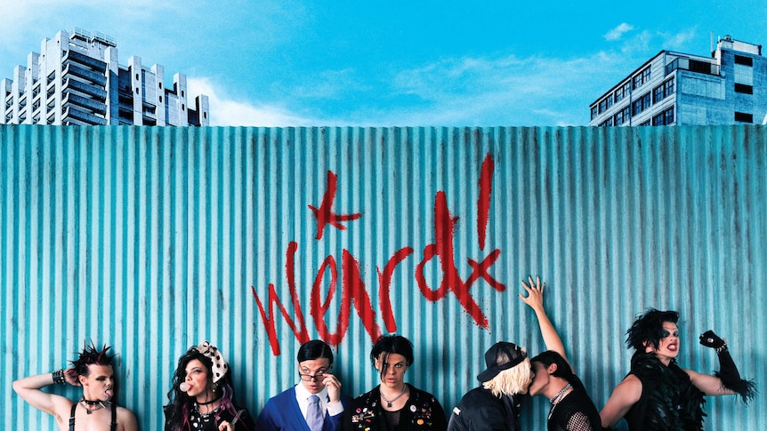 Image shows YUNGBLUD dressed up as 7 different characters & the word 'weird!' graffitied on a fence
