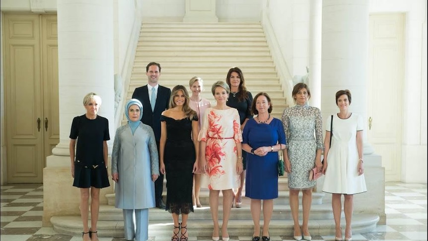 Nine first ladies and the first gentleman of Luxembourg pose for a photo at the bottom of a staircase.