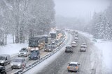 Snow falls as vehicles move bumper-to-bumper along the motorway near Albertville, the French Alps, on December 27, 2014