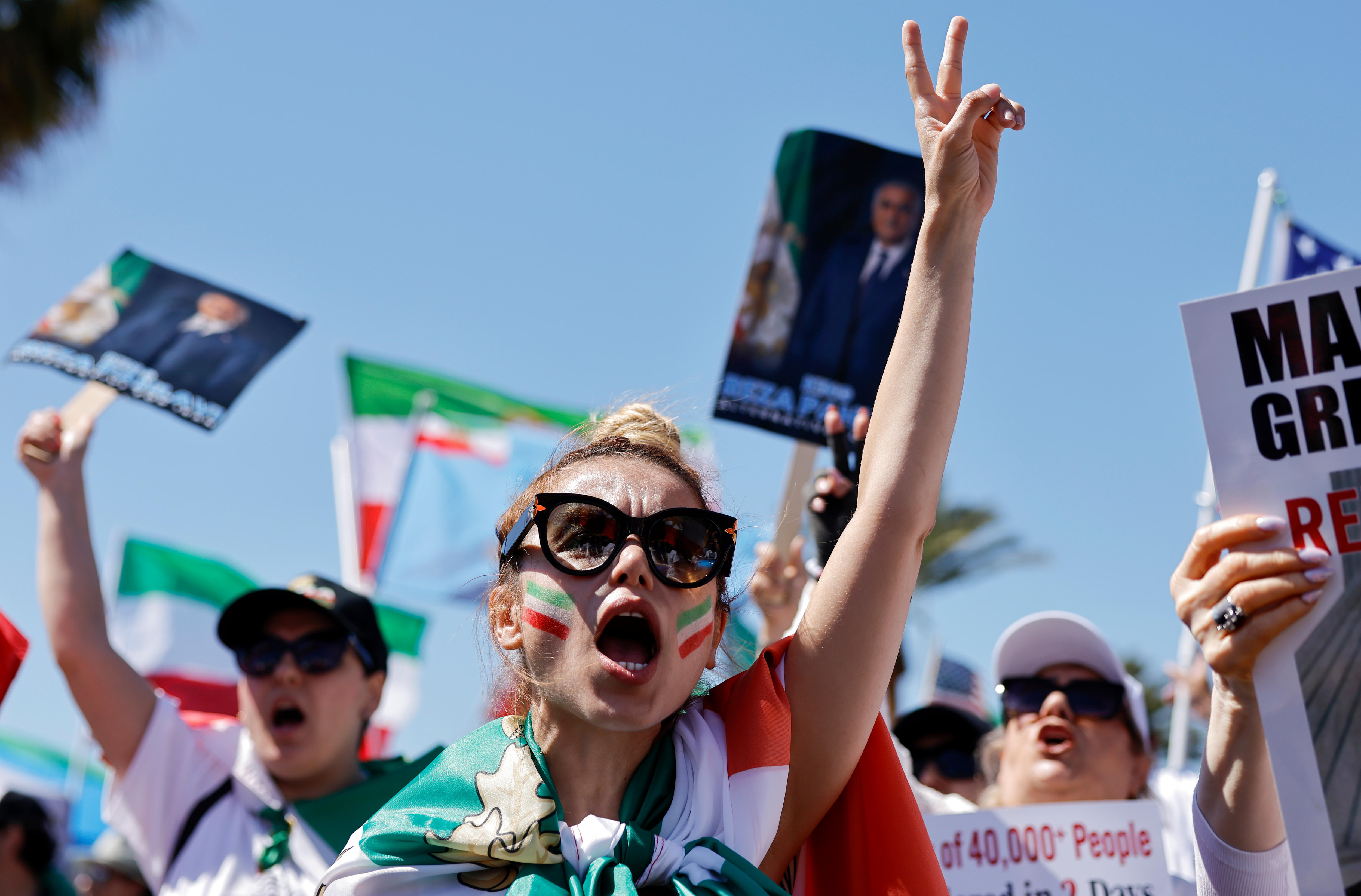 A protester draped in an Iranian flag holds her fingers up