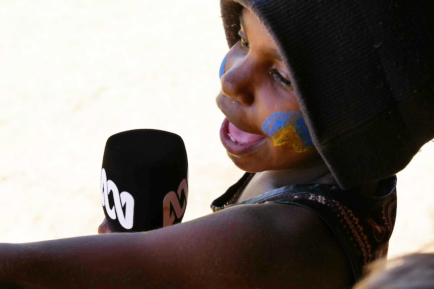 A child from Balgo, Western Australia holds a microphone.