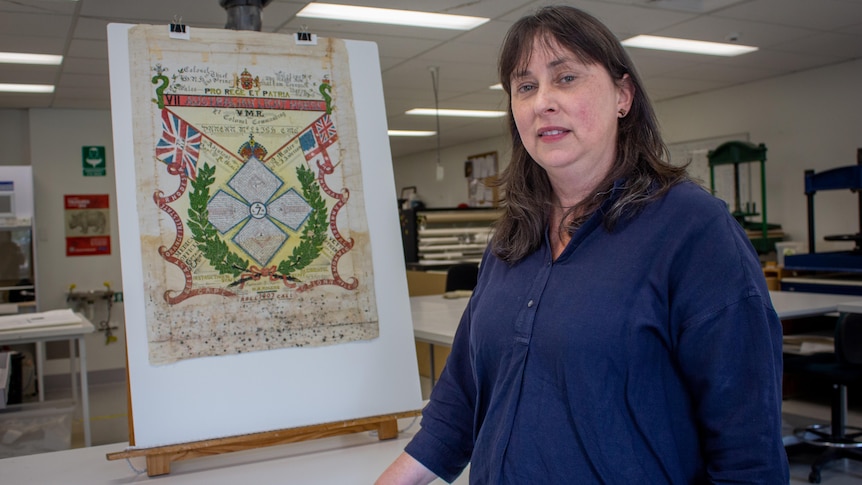 A rare print on an easel with a woman standing in front of it