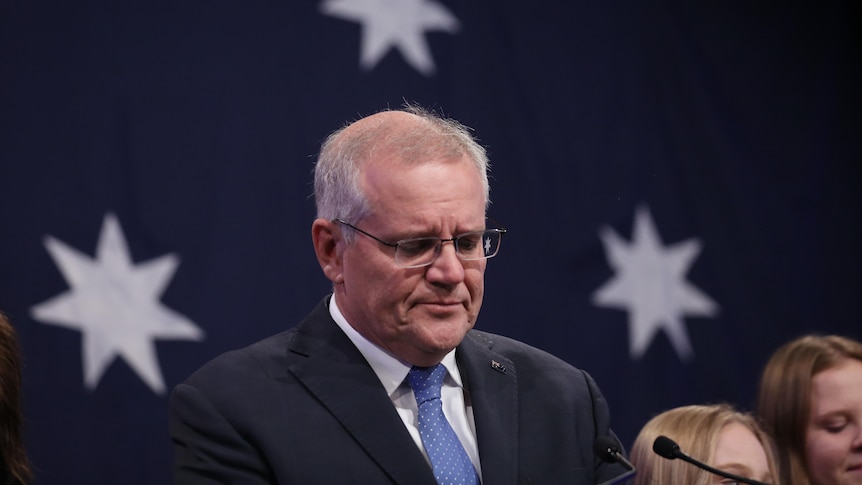 Outgoing prime minister Scott Morrison looks glum standing in front of an Australian flag after the 2022 federal election.