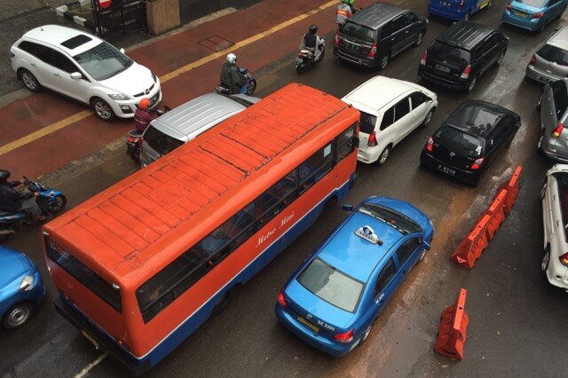 An orange Metro Mini private bus on the streets of Jakarta